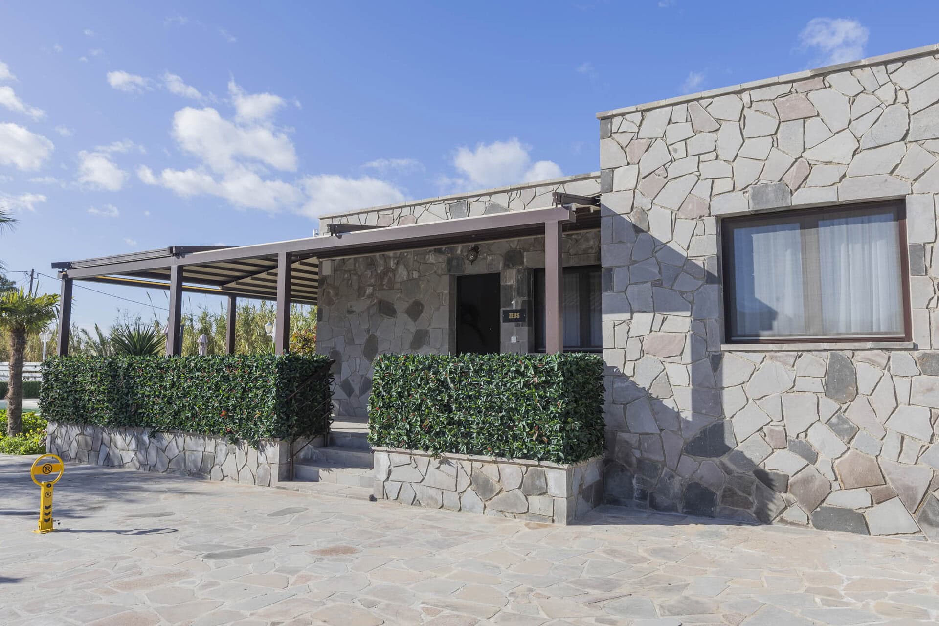 Exterior view of stone bungalow with private terrace at Adonis Aegina Bungalows