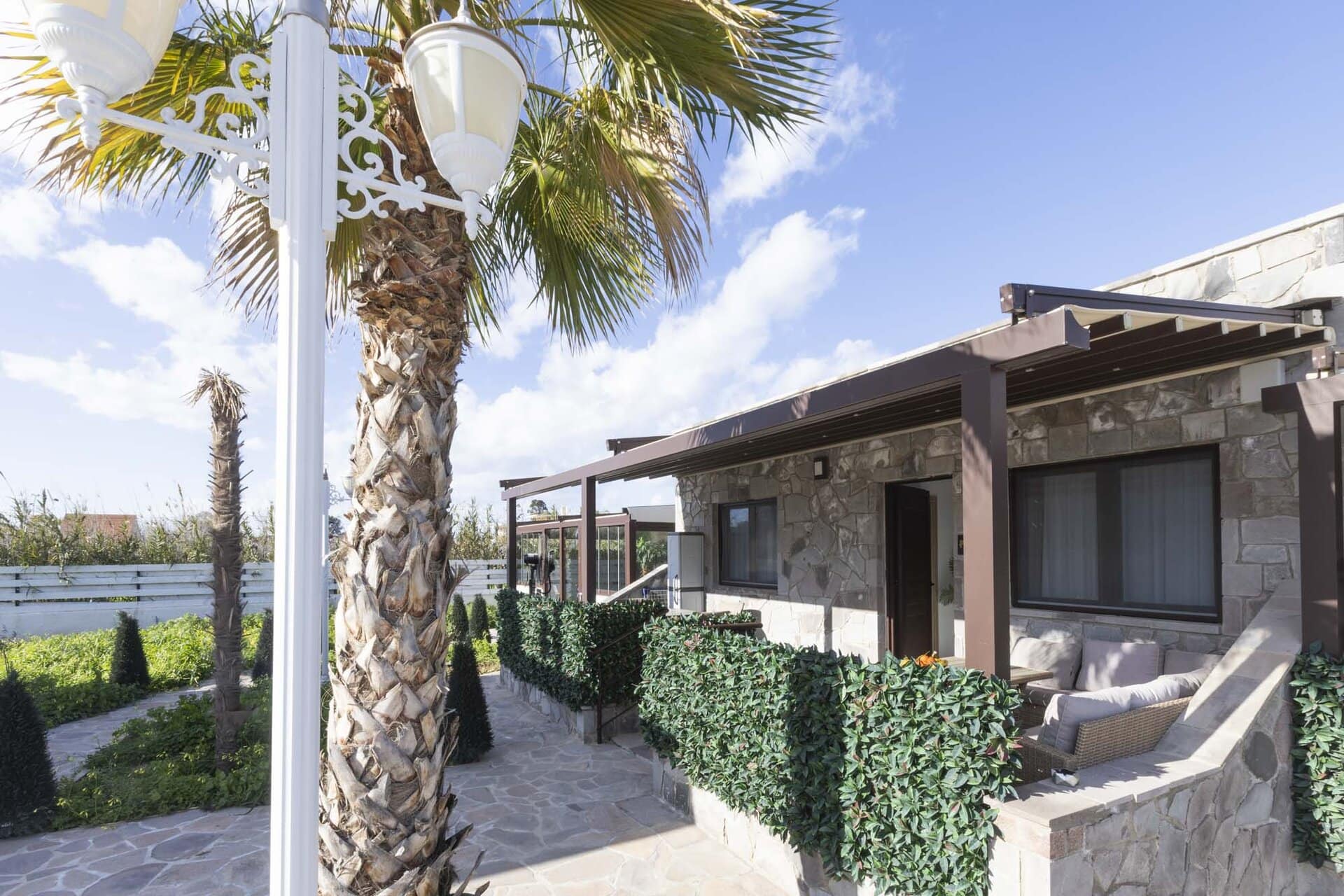 Exterior view of Bungalow Poseidon with palm trees at Adonis Aegina Bungalows